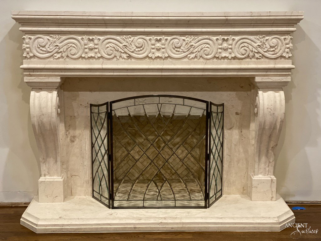 Reclaimed antique limestone fireplace mantel by Ancient Surfaces carved with a rinceau acanthus frieze above scrolled volute corbels and a single piece hearth