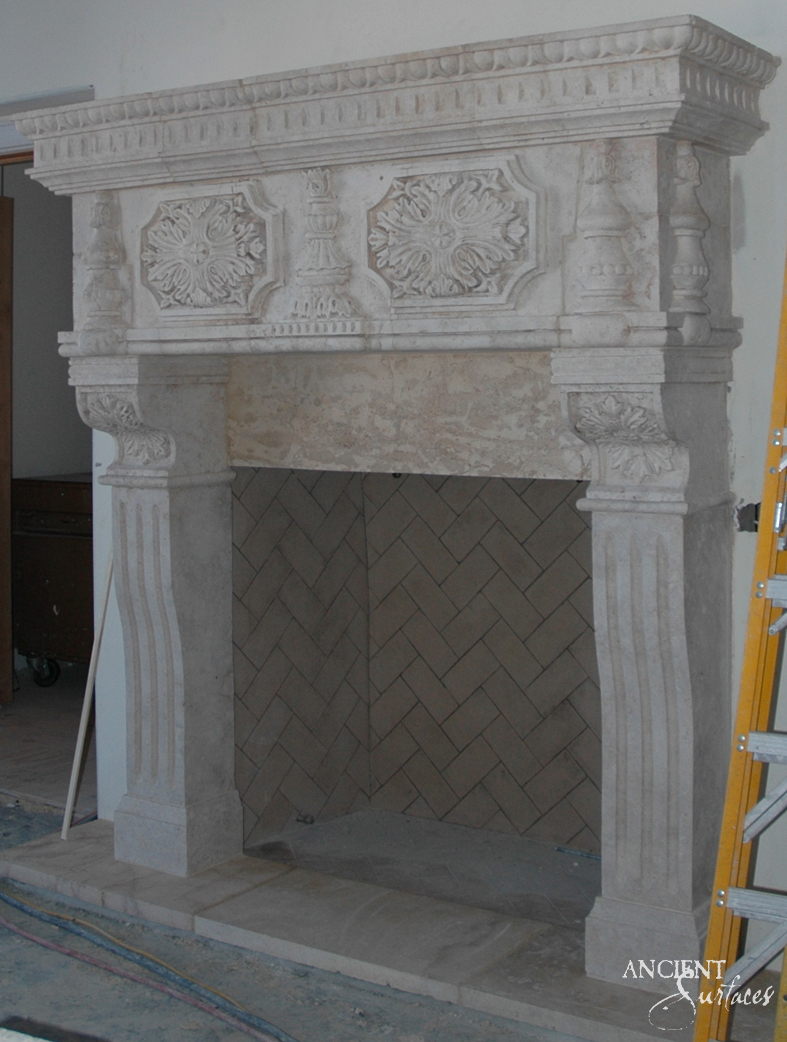 Hand carved limestone chimneypiece by Ancient Surfaces with a panelled overmantel of rosette medallions and balusters above a herringbone firebox