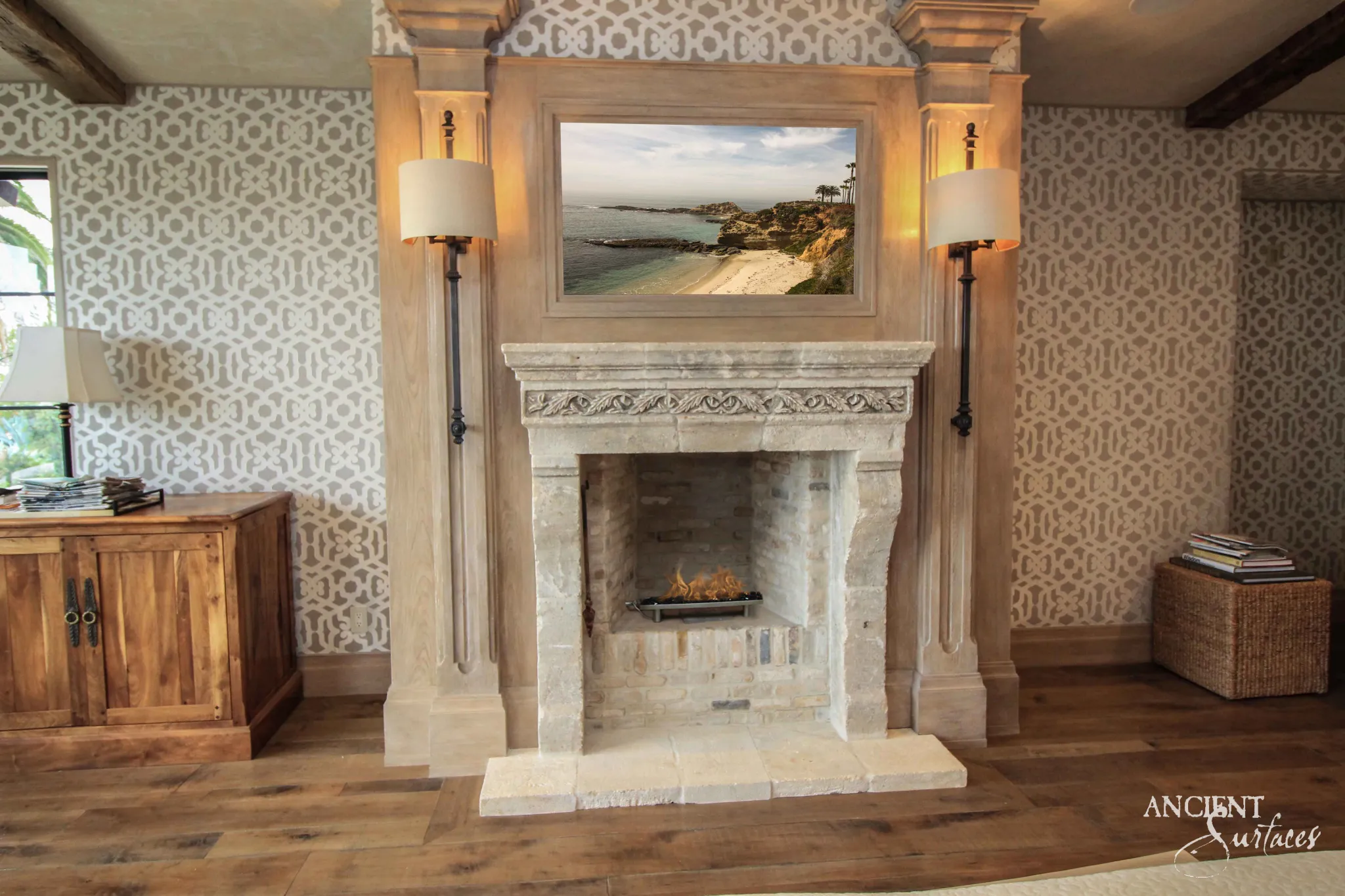 Reclaimed antique limestone fireplace mantel from Ancient Surfaces with a carved leaf and berry frieze in a bedroom suite between tall sconces