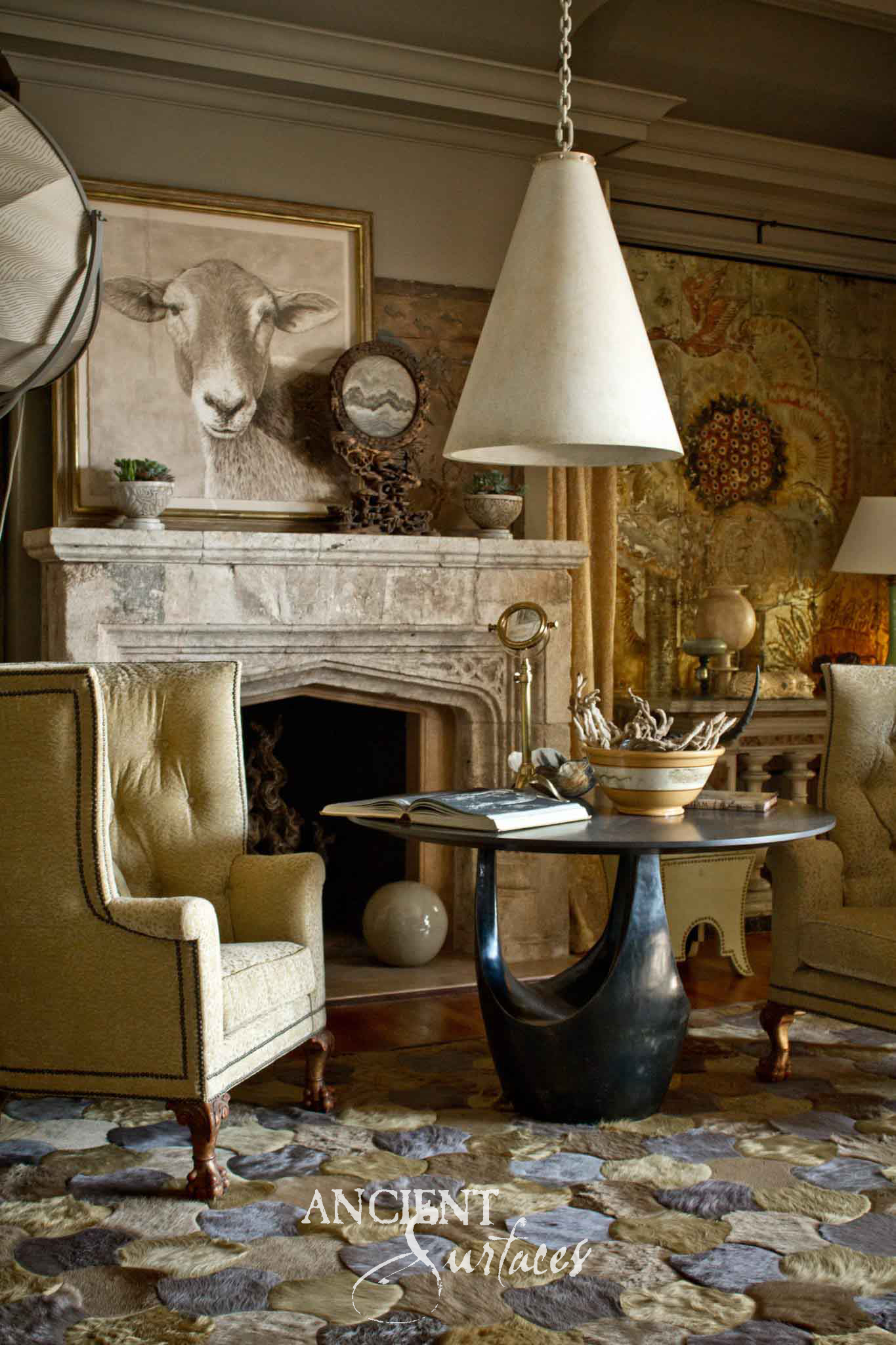 Ancient Surfaces weathered grey reclaimed limestone fireplace mantel with a segmental arched opening in an antiquarian room