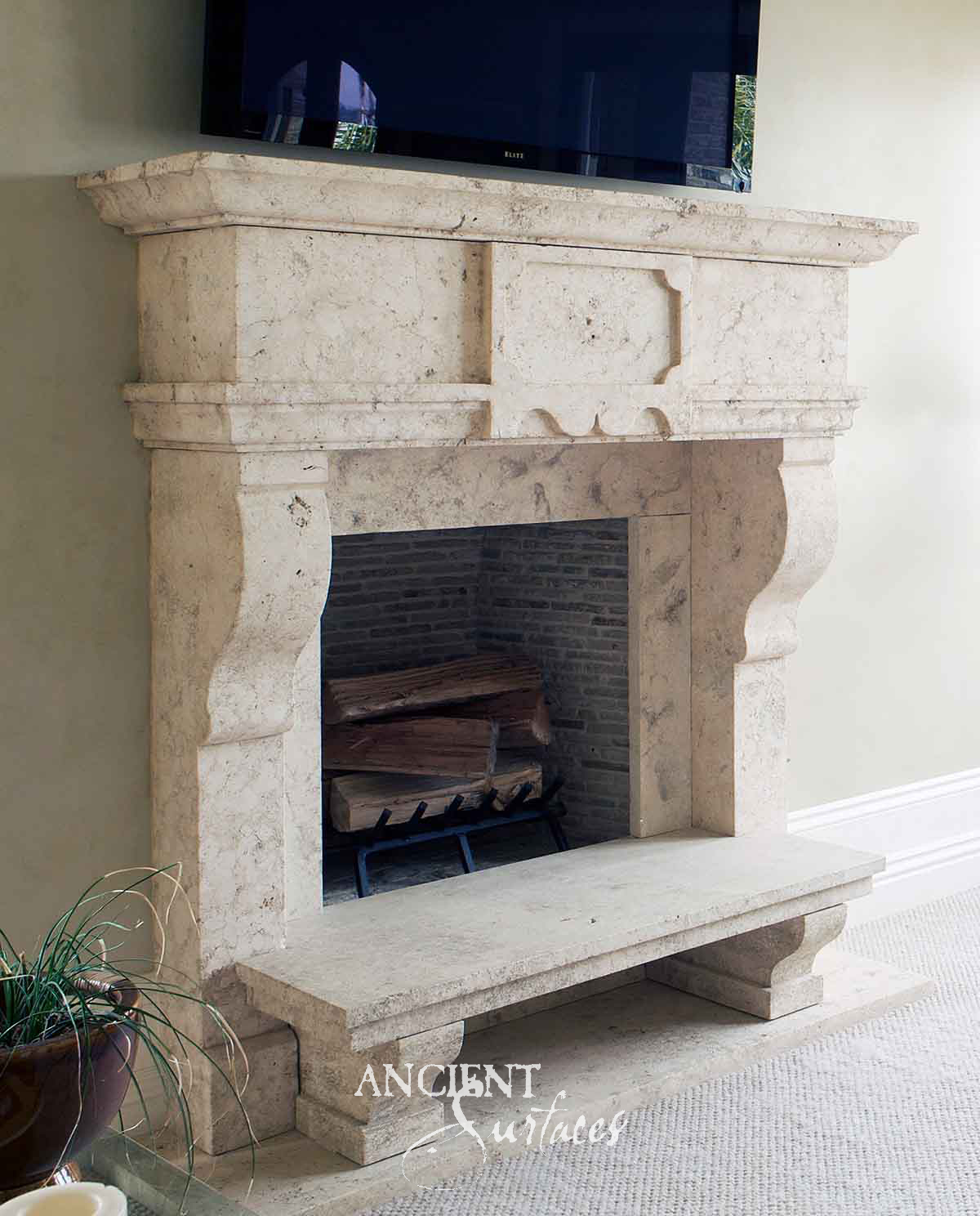 Ancient Surfaces reclaimed fossilised limestone chimneypiece with a panelled overmantel and cantilevered stone hearth bench
