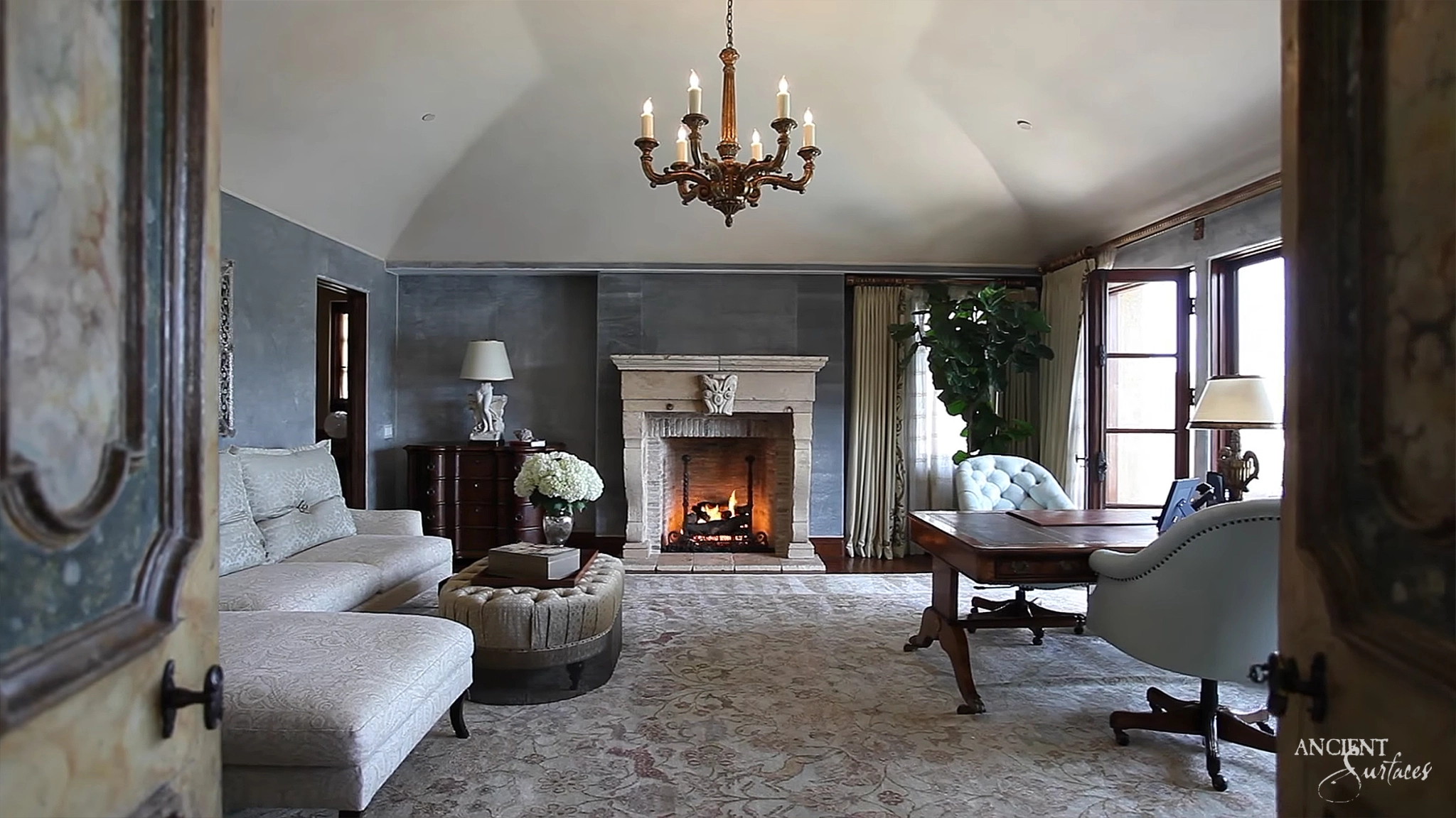 Ancient Surfaces reclaimed limestone fireplace mantel with carved scroll corbels burning in a barrel vaulted study