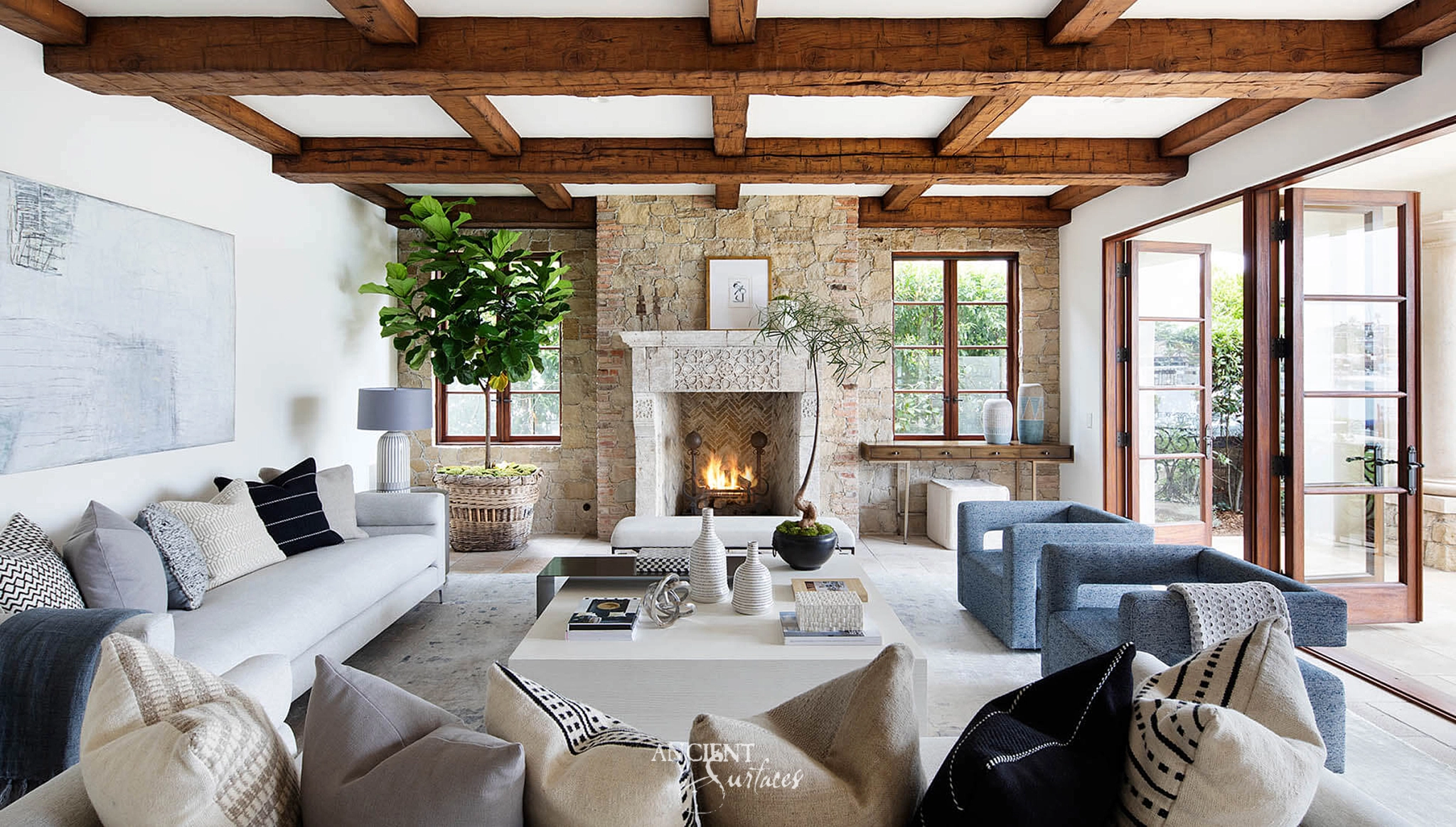 Ancient Surfaces minimal reclaimed limestone fireplace mantel with an arched firebox in a white beamed living room