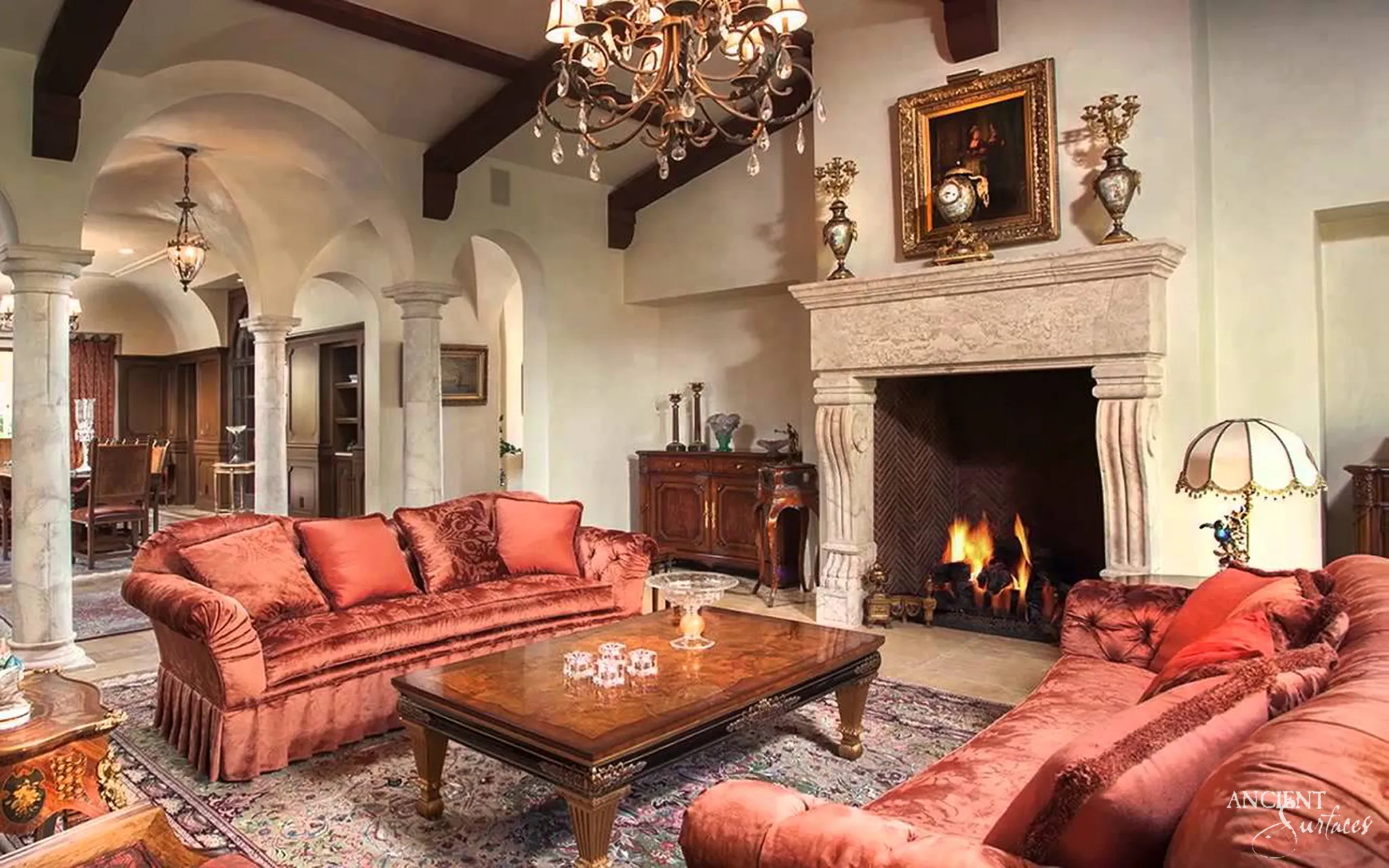 Grand reclaimed Italian limestone fireplace mantel from Ancient Surfaces with a heavy moulded shelf and fluted corbels in a vaulted Tuscan living room