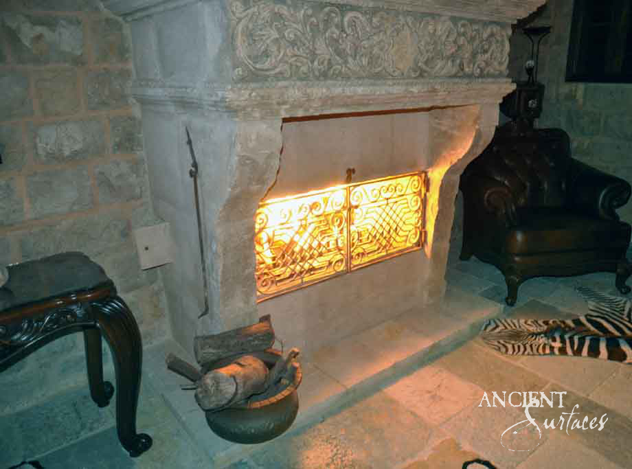 Monumental reclaimed antique limestone chimneypiece from Ancient Surfaces with a deeply carved mythological frieze of winged beasts above a wide firebox