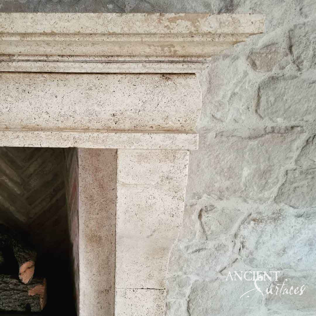 Close detail of a reclaimed antique limestone mantel shelf from Ancient Surfaces showing moulded profiles, fossil shells and hand tooling in the stone
